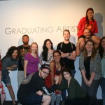 group of students standing in front of a wall that says "graduating artists"
