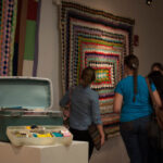 Guests looking at a quilt behind sewing supplies