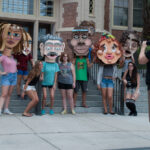 Students and cardboard heads get their photo taken in front of Westcott