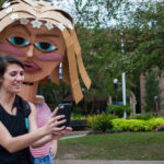 A female student and cardboard head share a photo that was taken