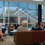 Back shot of group of graduate students listening to Jean Massing
