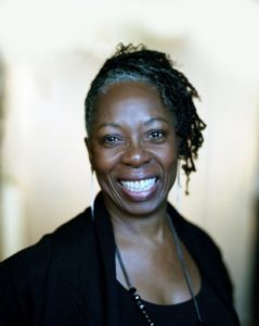 A woman smiling, wearing a black shirt. 