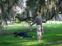 Two dancers perform beneath a live oak tree covered in Spanish moss.