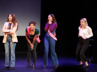 Four women stand on stage looking excited.
