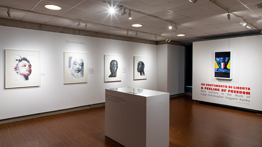 An exhibit in a museum highlights portraits, which are well lit and hanging on white walls. 