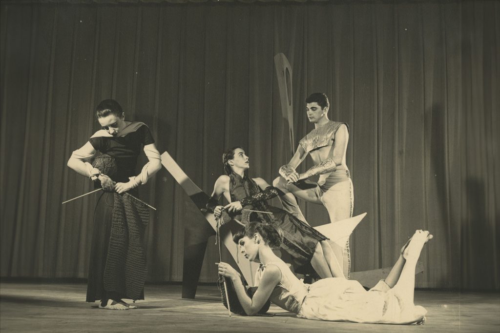 People in costume perform on a stage in this vintage 50s photo.