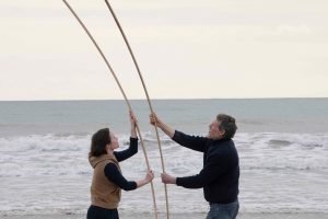 Two people are holding up sticks on a beach