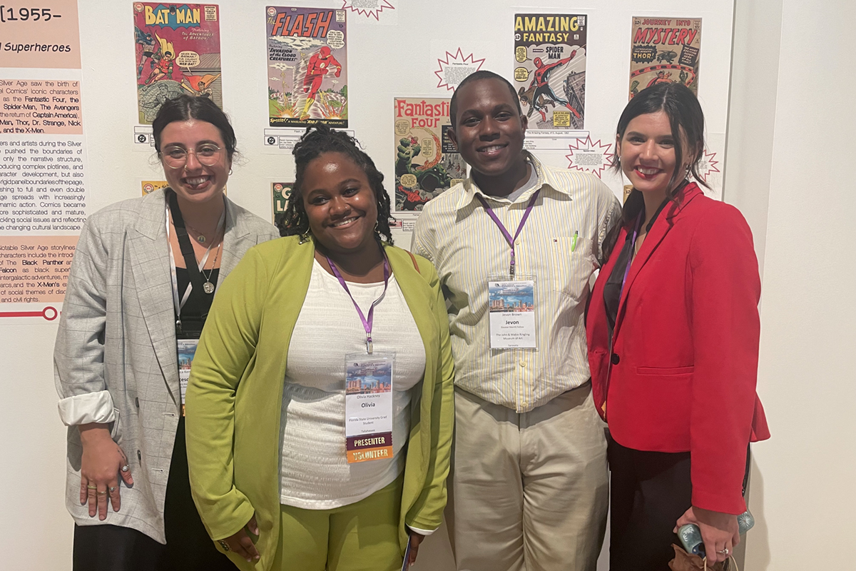 four people standing next to each other in front of a wall of comic books