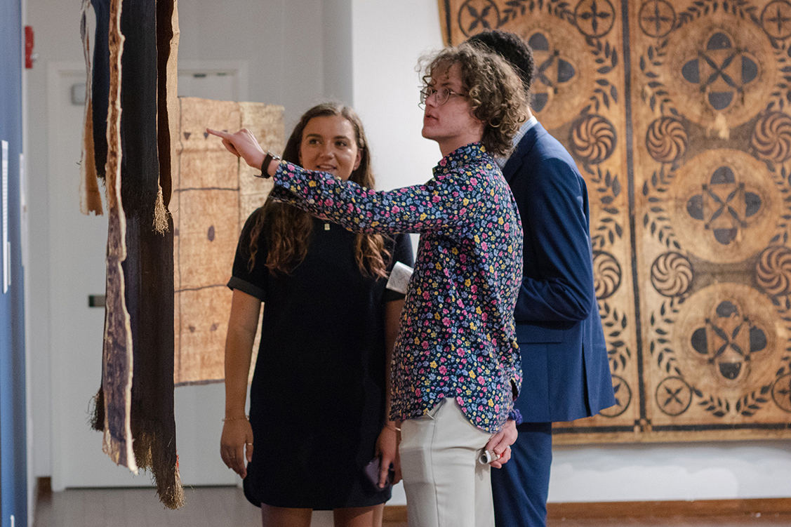 two people looking at a piece of fabric on display