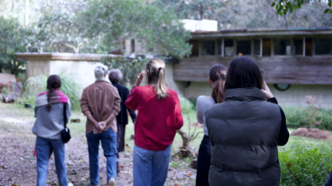 Students walk ahead of the camera looking at a midcentury modern structure in the distance