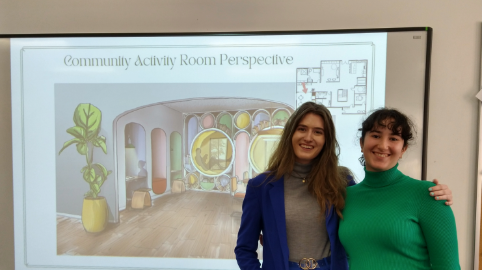 Two young women pose in front of a presentation