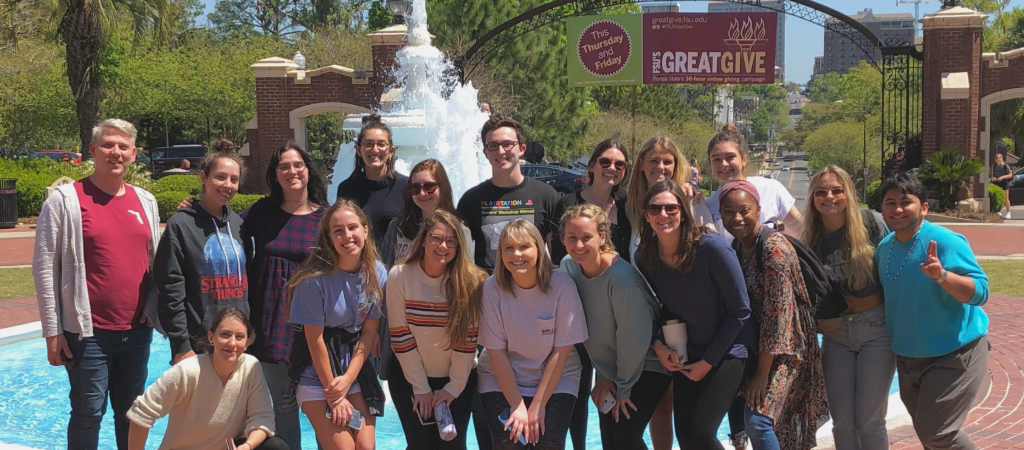 A group of students pose smiling in front of Wescott Fountain