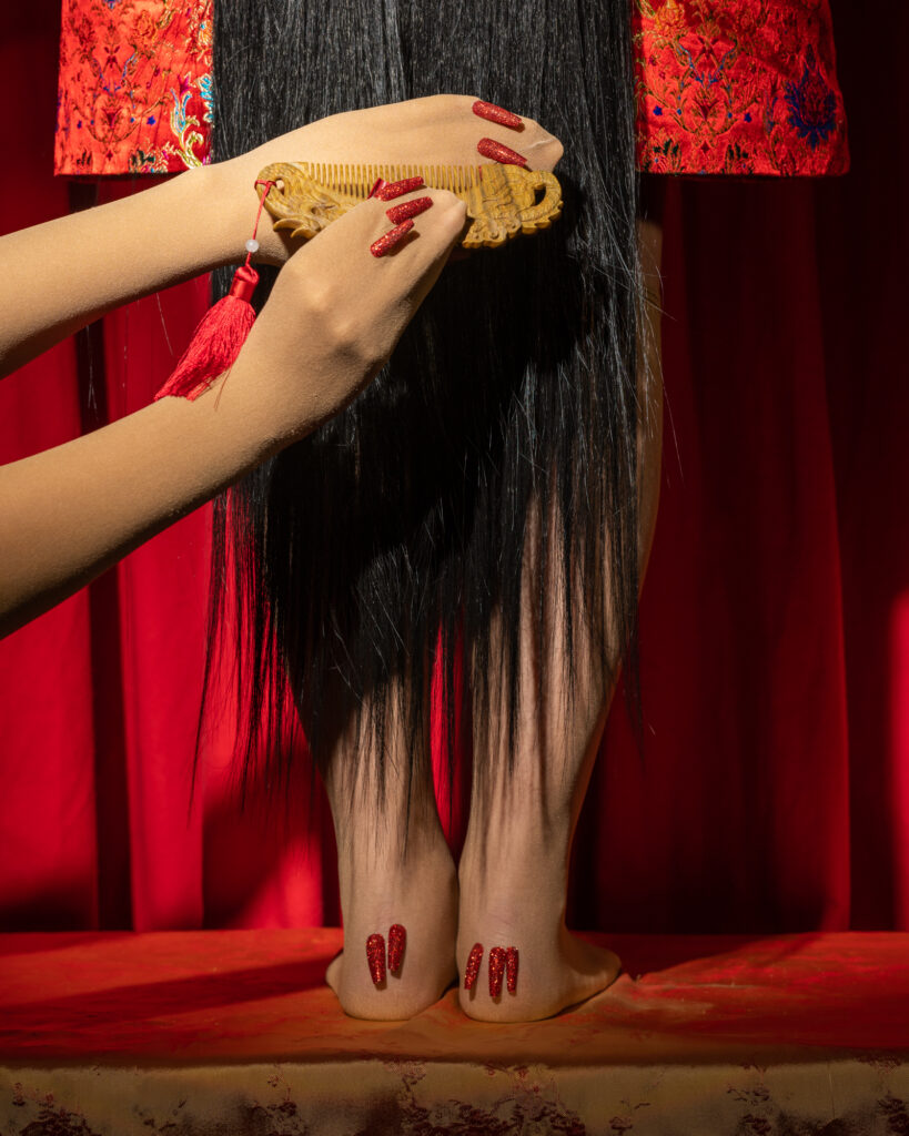 a woman with long black hair and red nail polish on her feet
