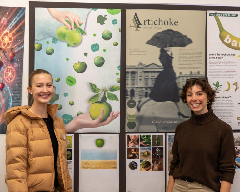 Two graphic design students pose with their work