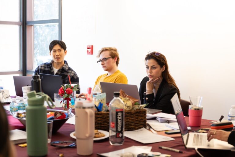 several people sitting at a table with laptops and papers