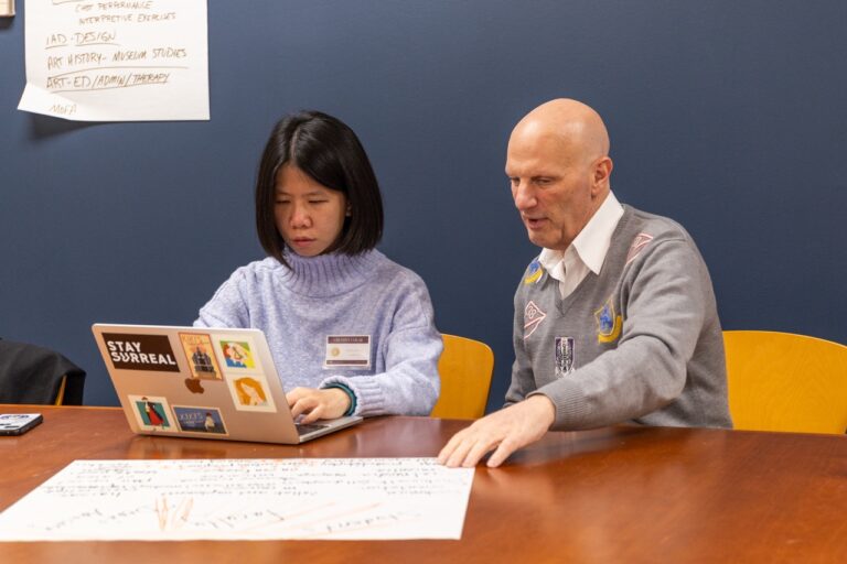 there is a man and a woman sitting at a table with a laptop