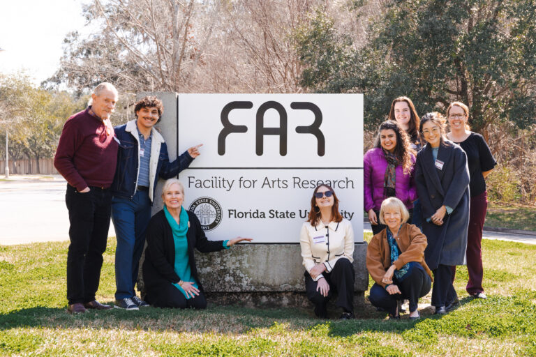 People pose for a photo around a sign that says "FAR"