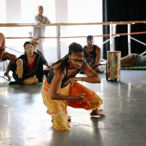 there is a woman that is kneeling down in the middle of a dance class