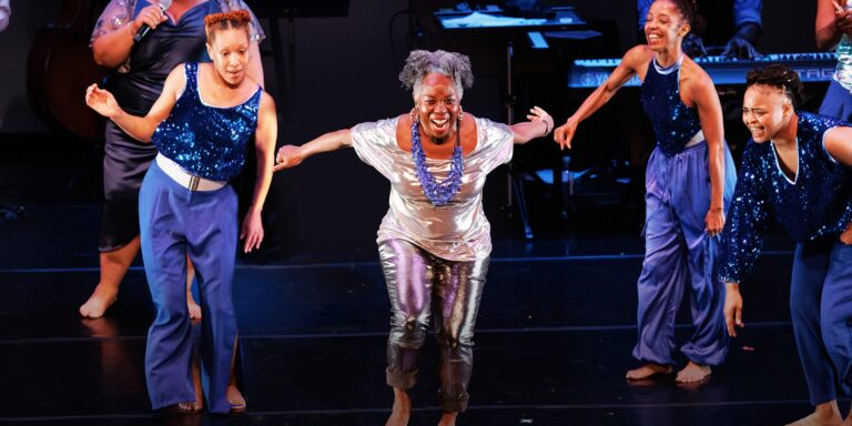 there is a woman that is dancing on a stage with other people