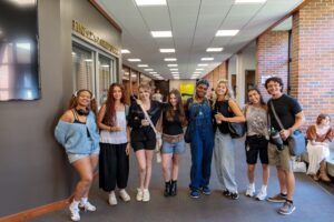 A group of college students pose for a photo in an academic building.