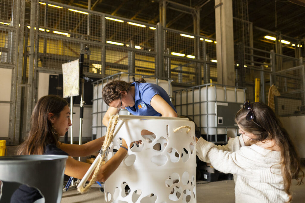 there are two women that are working on a bucket in a factory