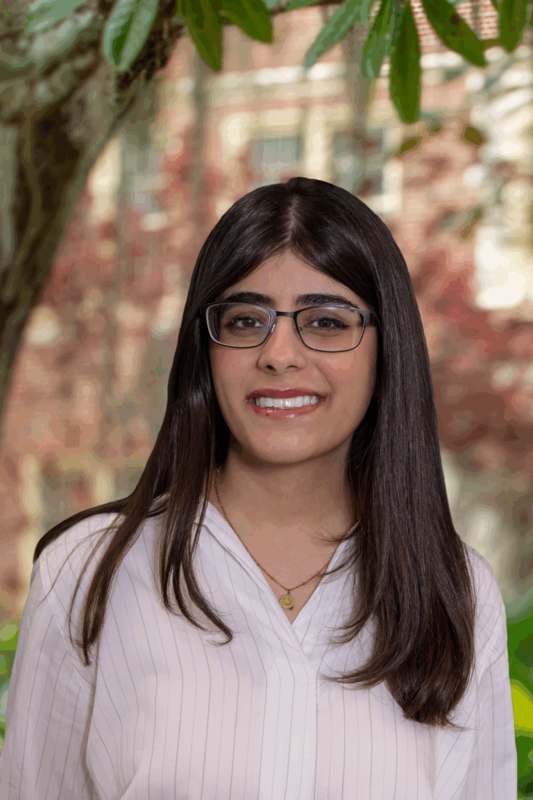 a woman with glasses standing in front of a tree