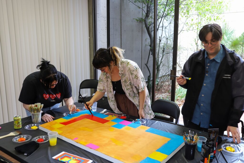 Three people working on a painting.