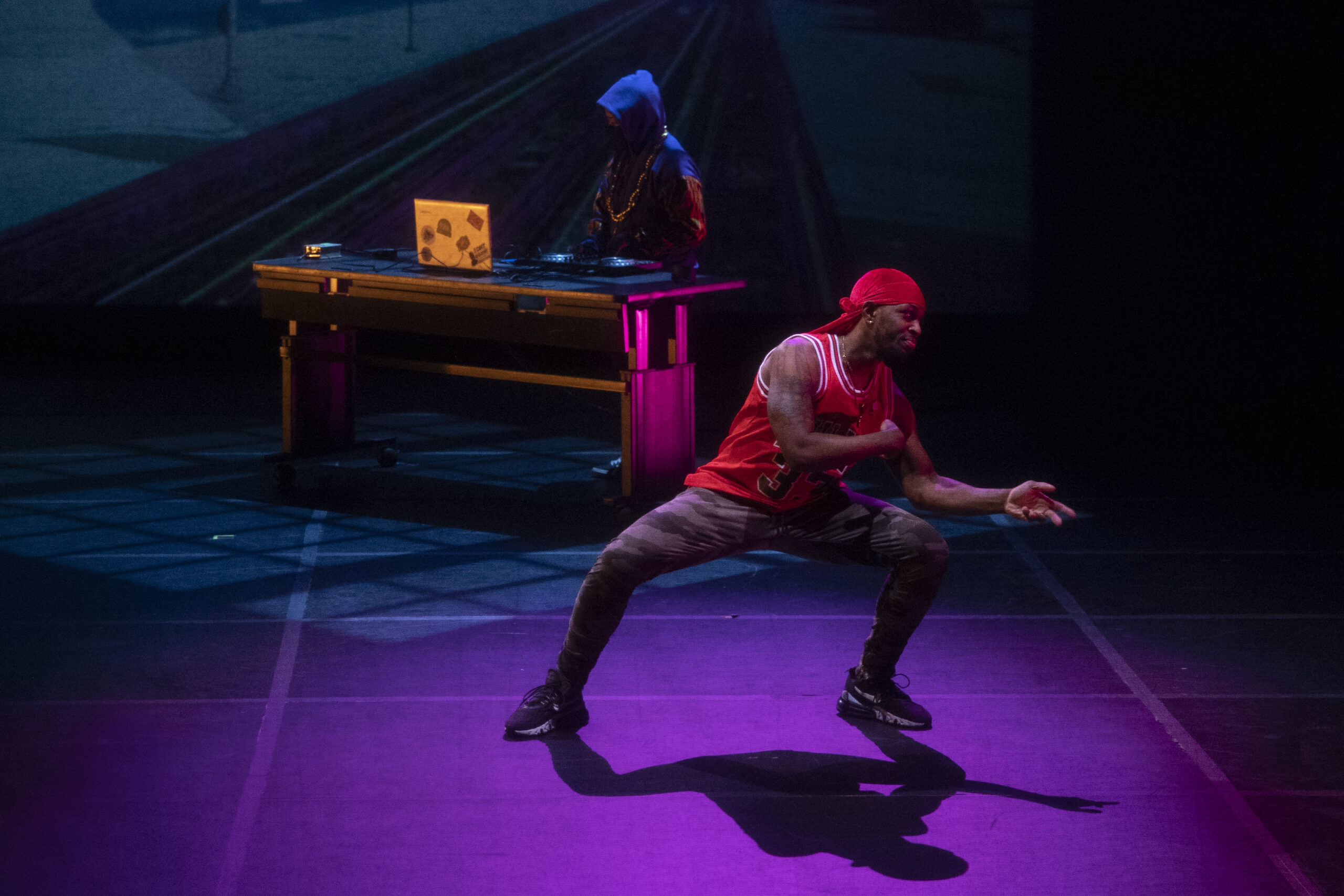musical dancing on stage with one person in front in a dance pose and another at the back playing piano