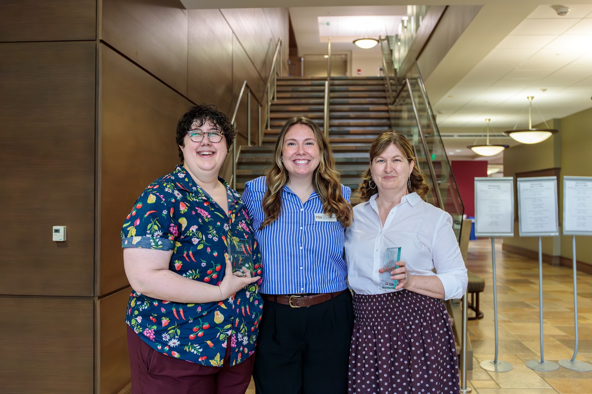 Three women in professional attire pose for a photo