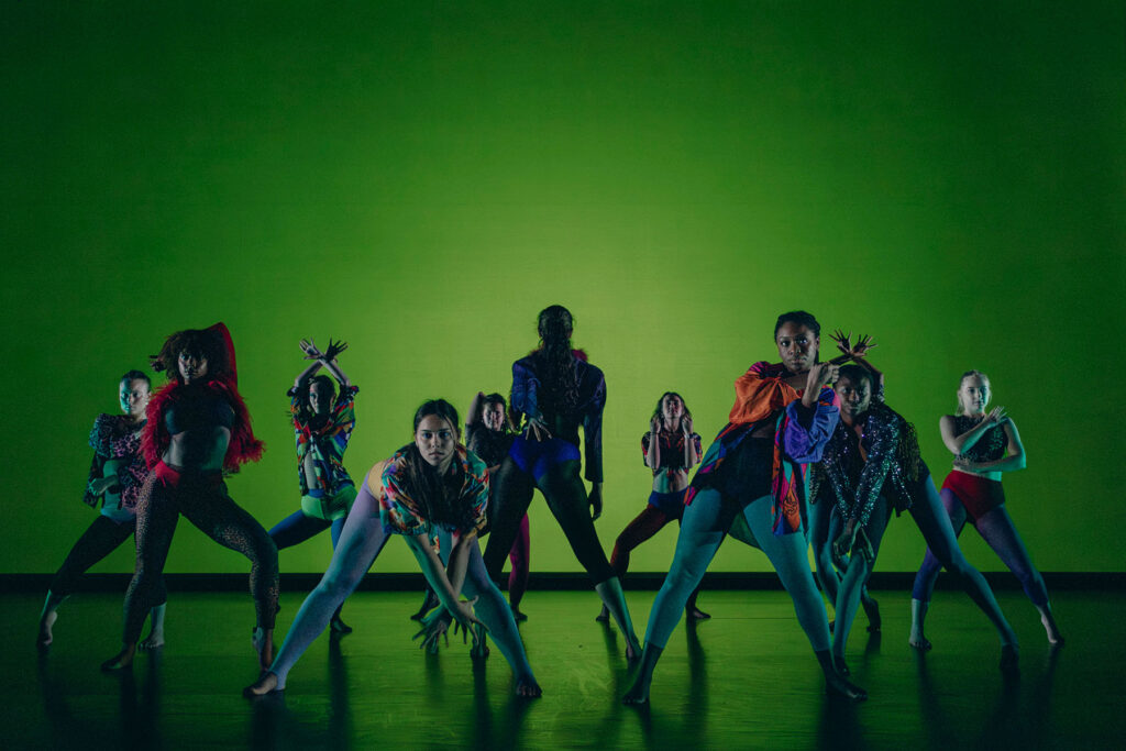 a group of dancers on stage with green background