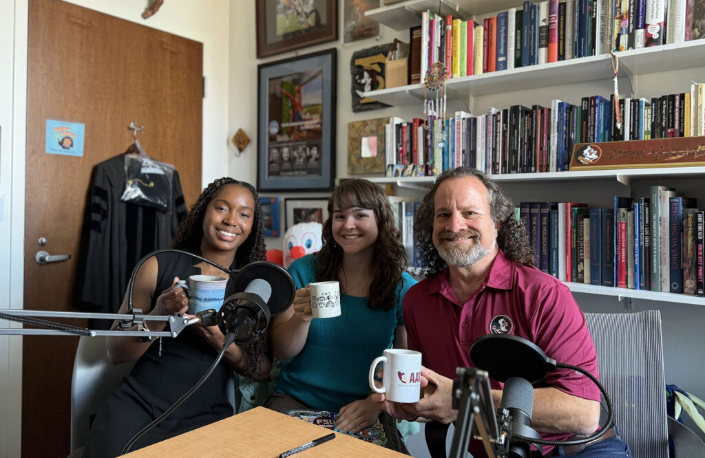 Three people holding coffee cups in front of a book case