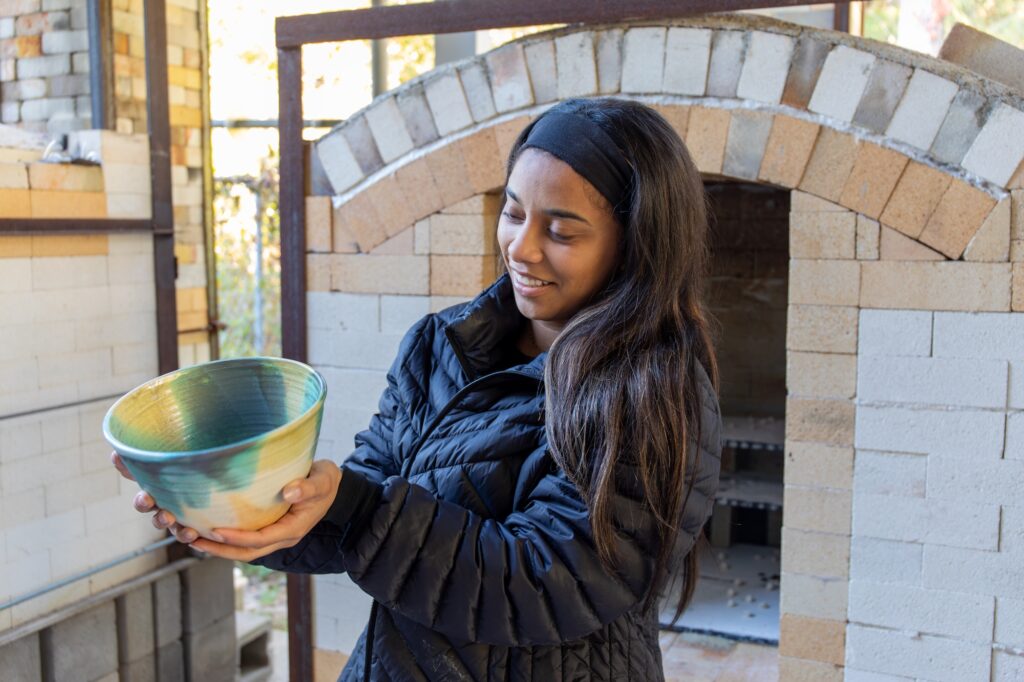 A young woman holding a ceramic vessel