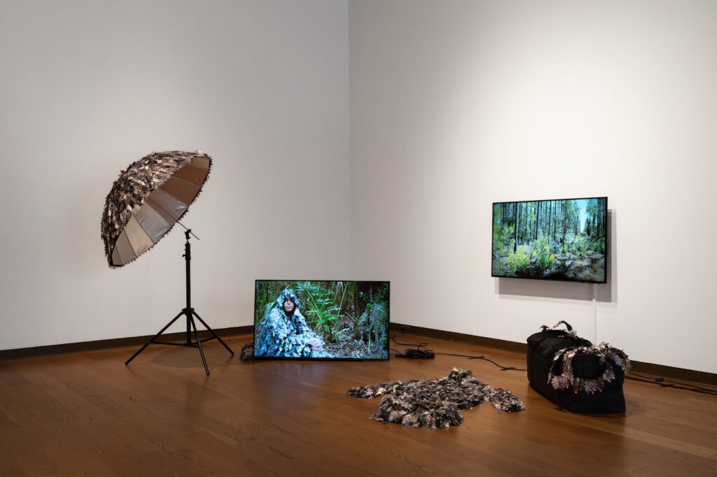 Two televisions and lighting equipment in a museum gallery