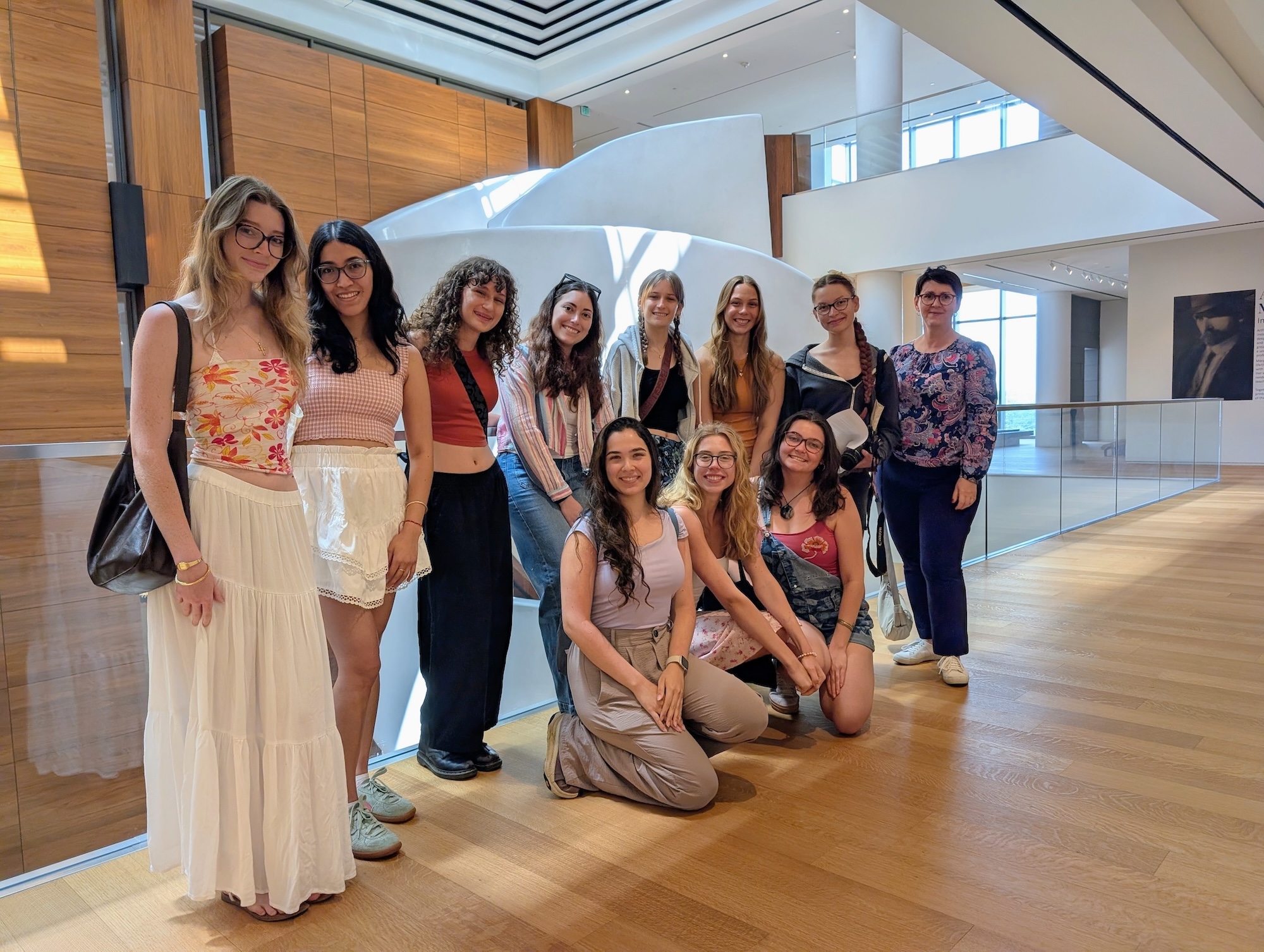 A group of women pose in a bright sunny room with wood floors
