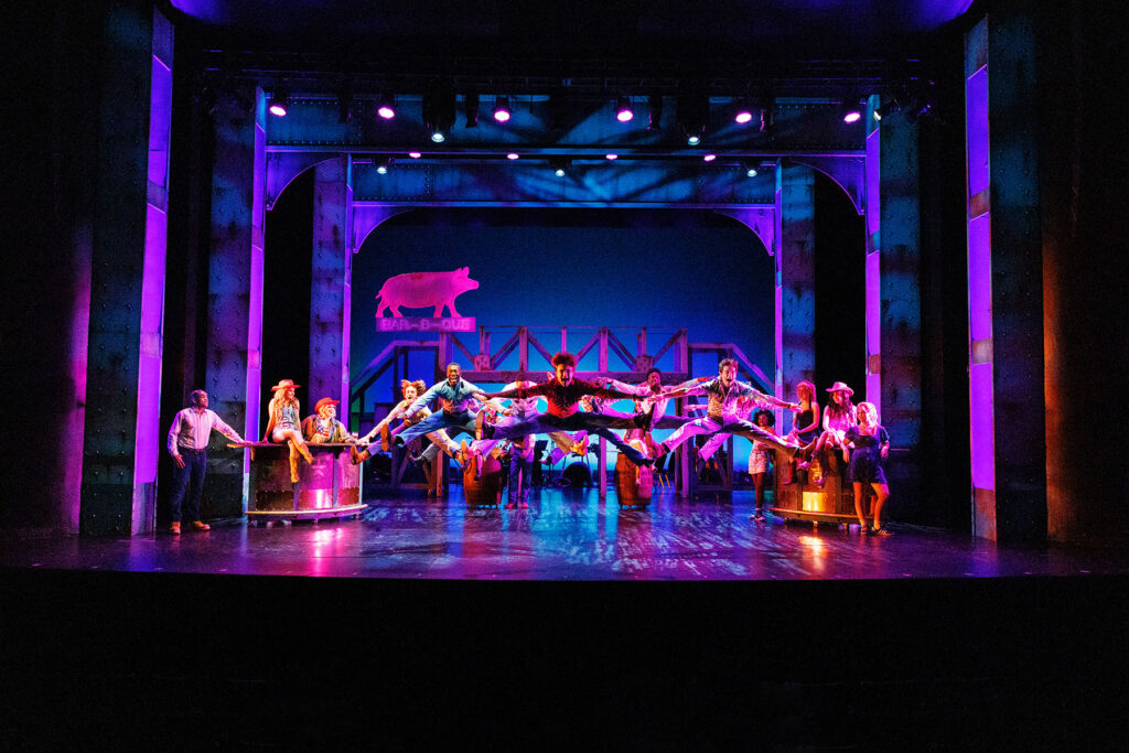 People dancing on stage. Purple and pink lighting in the background