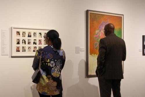 Two people look at works of art in a gallery