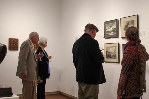 A group of people admire art in a gallery.