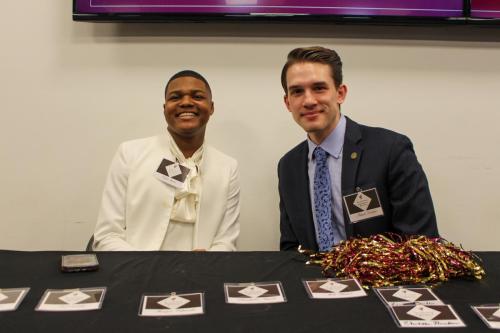 Two young men sit smiling at a table