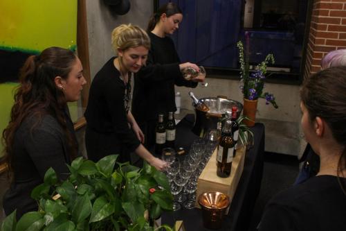 Women serve wine at a fancy event.