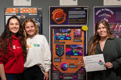 Student Haley Valtz, right, and teammates pose with their pinball-inspired charrette project. (Ivan Peñafiel)